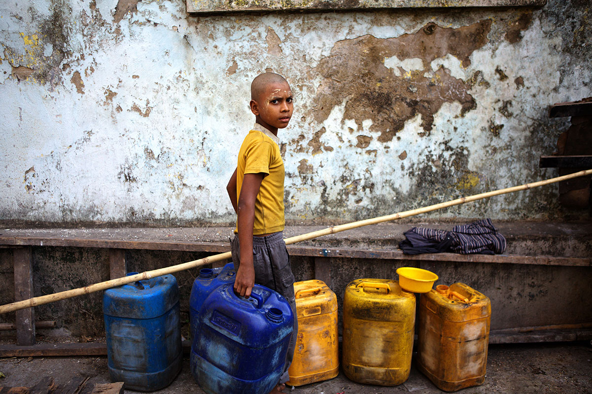 Working child wearing thanaka against colonial backdrop