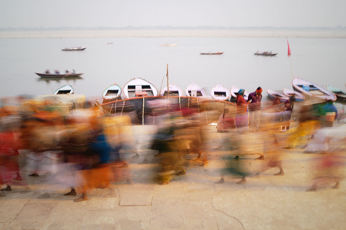 Blurred crowd shot of time while boats sail on the Ganges