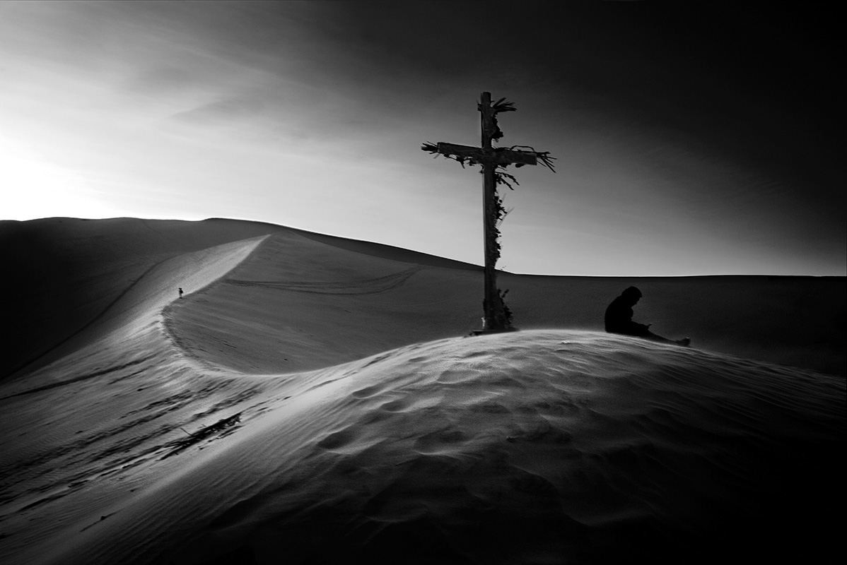Christian cross overlooks lonely figure in desert