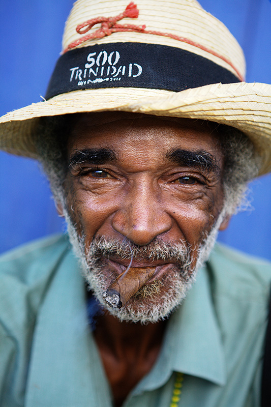 Kind faced Cuban man smokes Montecristo cigar