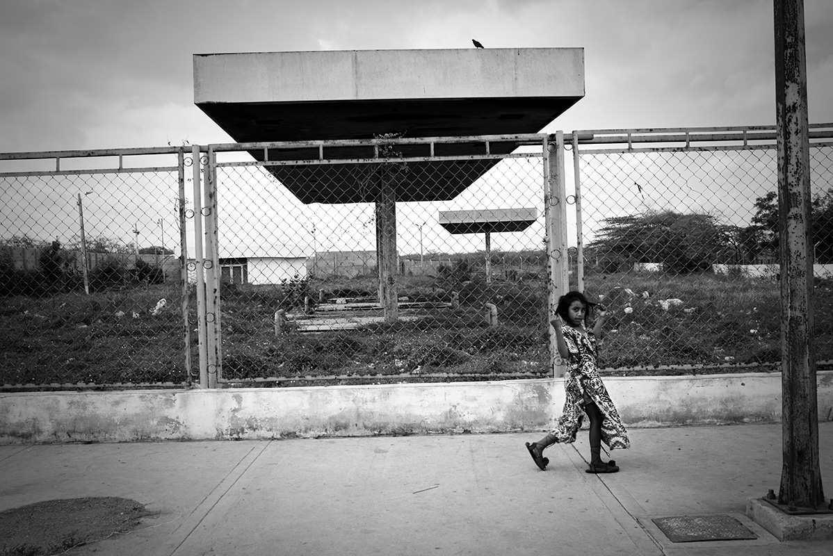 Young girl with homemade shoes crosses wasteland