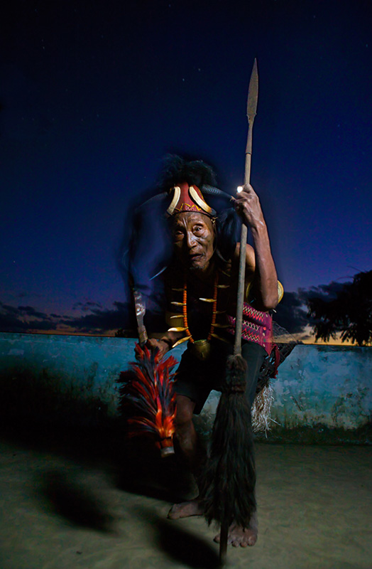 Headhunting man dances with spear at sunset